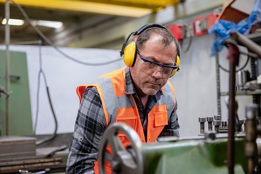 Industrial paging in noisy environments. Image of an industrial worker wearing hearing protection in an industral plant